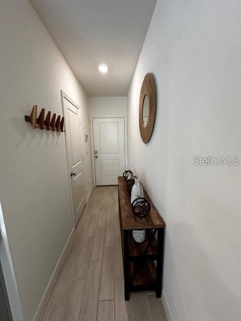 A narrow hallway features light wood-look tile flooring, a console table, and a wall-mounted mirror — 1631 MIRABELLA CIRCLE, DAVENPORT, FL