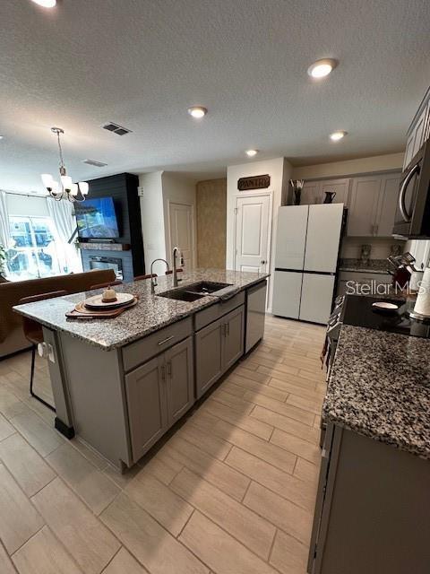 A kitchen features a granite-topped island, light wood-look tile flooring, and stainless steel appliances — 1631 MIRABELLA CIRCLE, DAVENPORT, FL