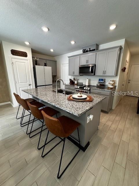 A kitchen features gray cabinets, granite countertops, a central island with bar seating, and tile flooring — 1631 MIRABELLA CIRCLE, DAVENPORT, FL