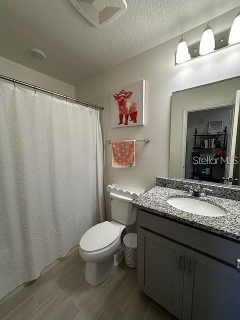 A bathroom features a granite vanity, a white toilet, and a shower with a white curtain — 1631 MIRABELLA CIRCLE, DAVENPORT, FL