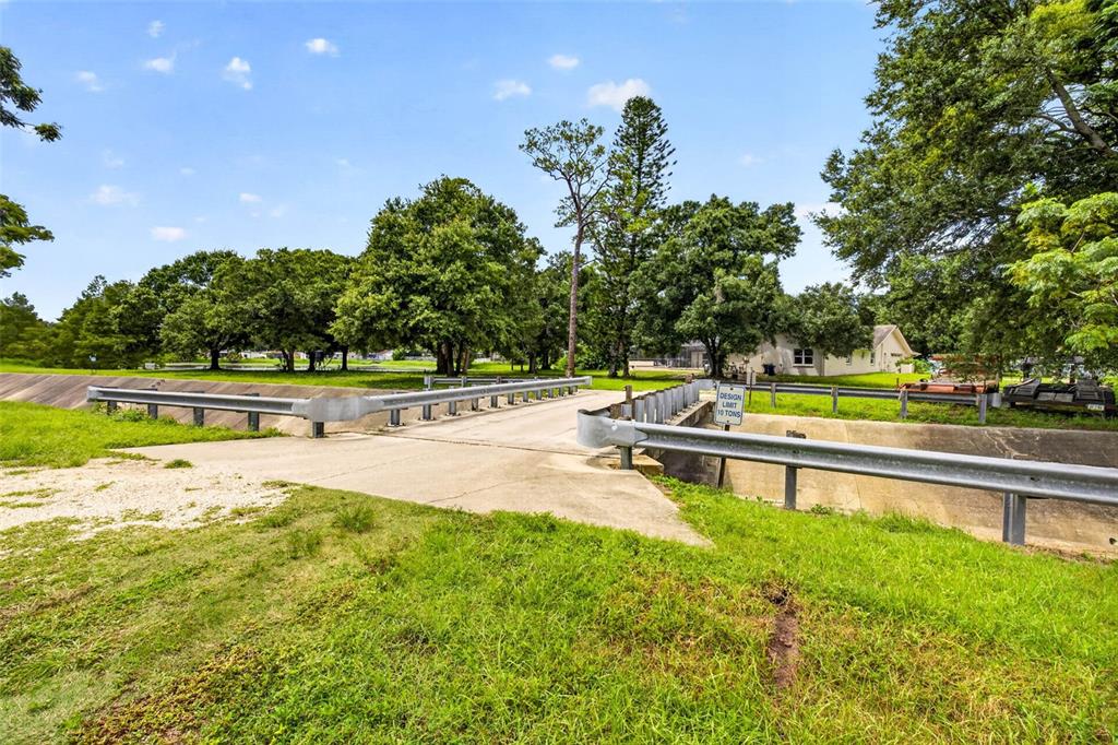 A concrete bridge with metal guardrails spans a drainage ditch in a grassy residential area — 6320 66TH AVENUE N, PINELLAS PARK, FL