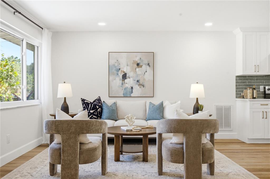 A living room features a white sofa, two tan armchairs, and a round wooden table — 1199 KEENE ROAD, DUNEDIN, FL
