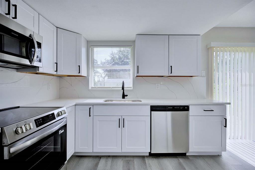 A modern kitchen features white cabinets, stainless steel appliances, and white quartz countertops with veining — 738 LEMANS DRIVE, SEBRING, FL