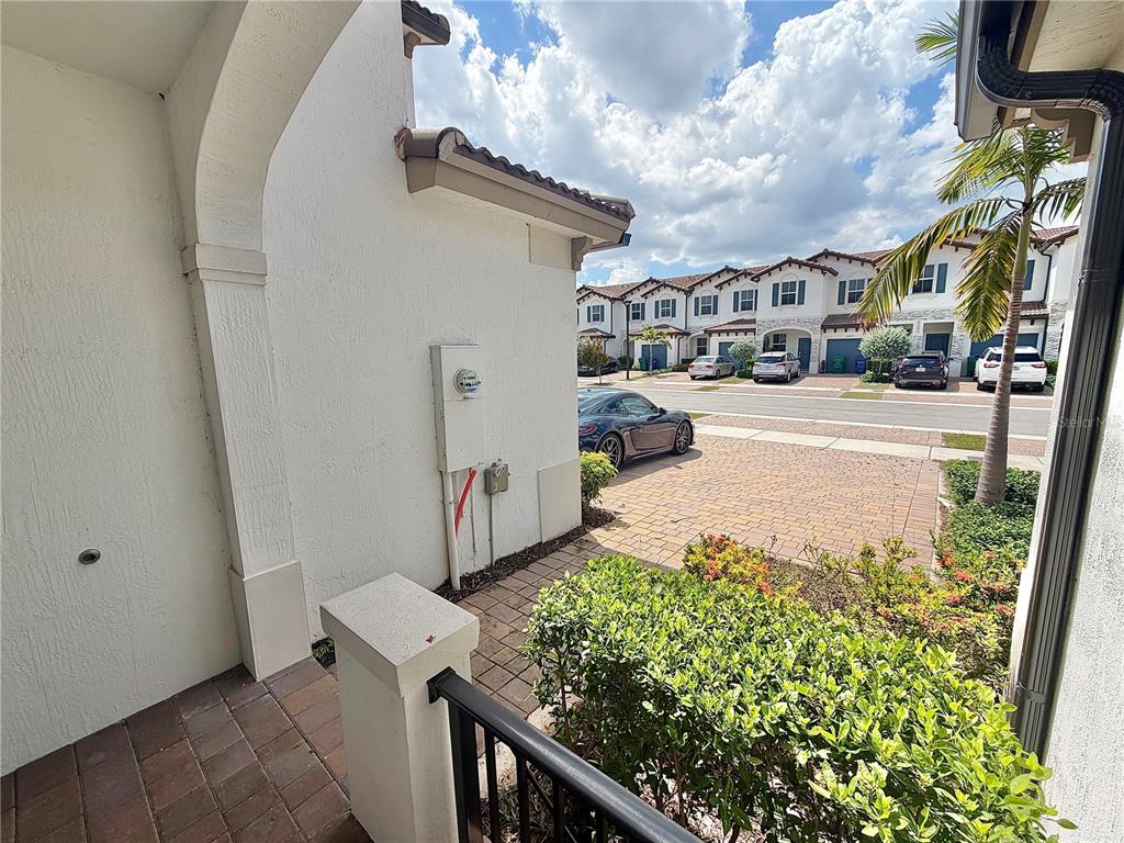 A view from a covered entryway looking out toward a paved driveway and townhouses — 12621 NW 23RD PLACE, MIAMI, FL