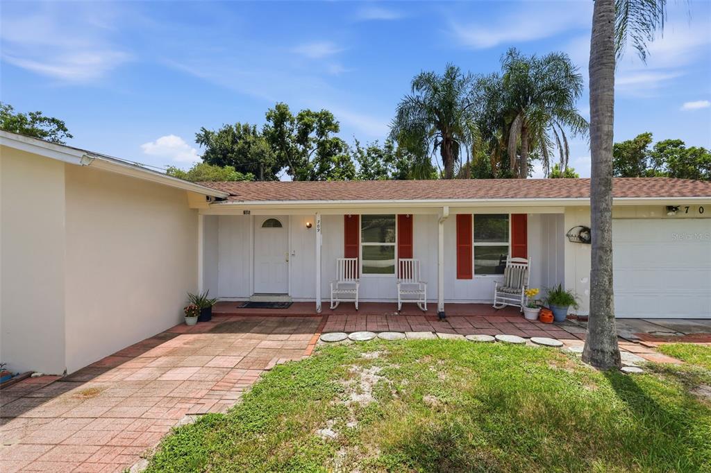 A single-story house with white siding, red shutters, a brick patio, and a garage — 709 HAGER STREET, DELTONA, FL