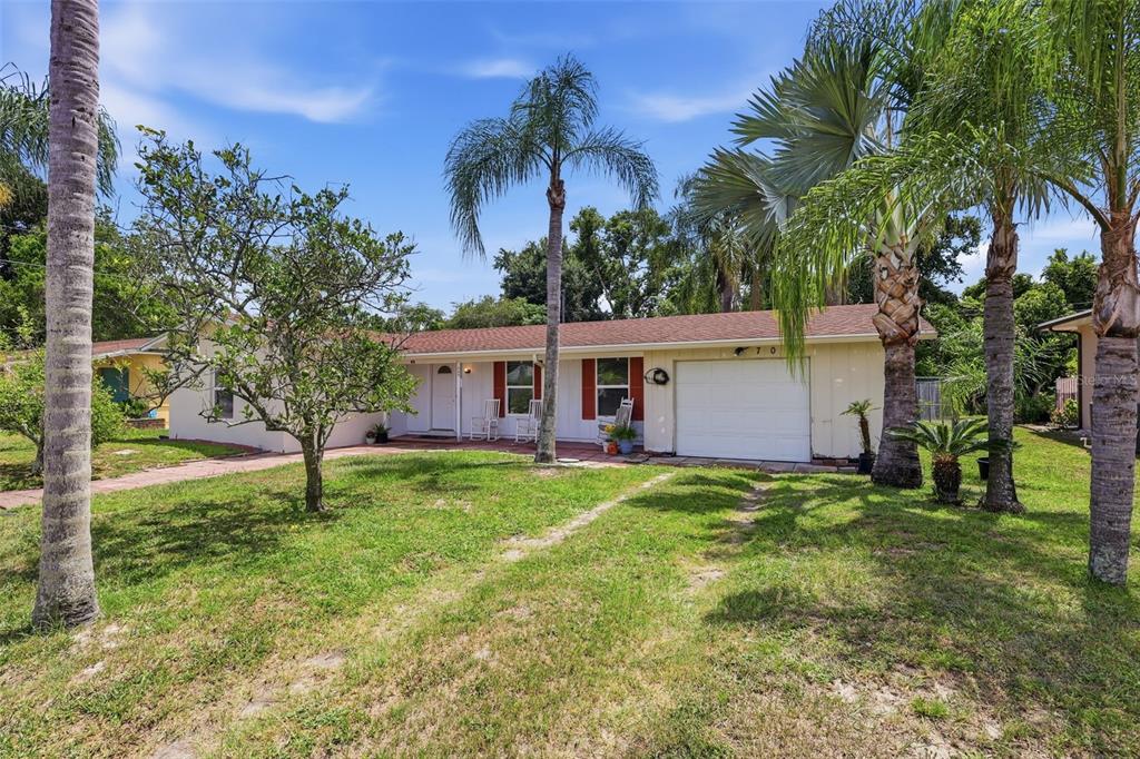 A single-story house with a white garage, red shutters, and several palm trees in front — 709 HAGER STREET, DELTONA, FL
