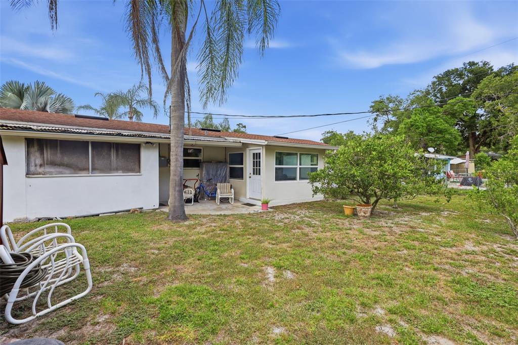 The exterior of a single-story house features a small patio, a palm tree, and lawn — 709 HAGER STREET, DELTONA, FL