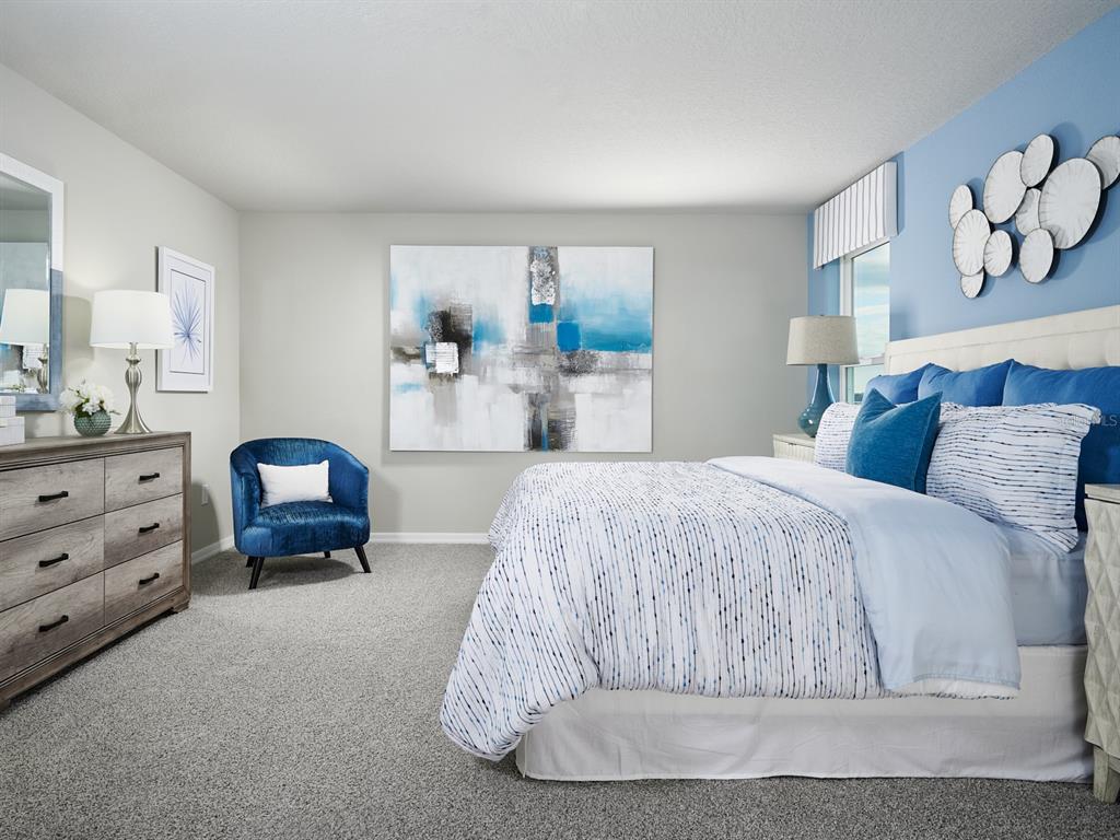 A bedroom features a bed with blue accents, a dresser, a blue chair, and wall art — 2876 WILD OLIVE DRIVE, ST CLOUD, FL