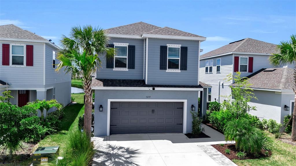 A two-story suburban house with gray siding, a two-car garage, and a palm tree — 5659 EQUATOR COURT, NOKOMIS, FL
