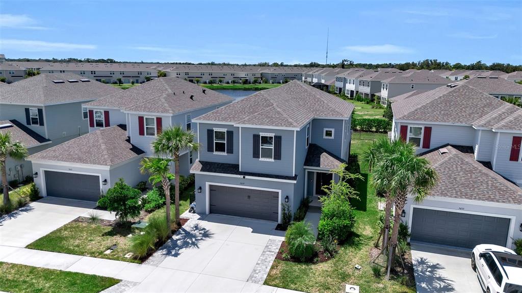 An aerial view shows several suburban houses with gray siding, shingled roofs, and attached garages — 5659 EQUATOR COURT, NOKOMIS, FL