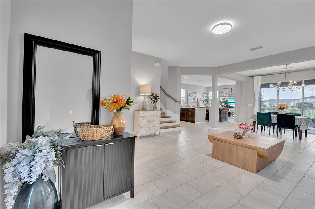 A bright, open-concept living and dining area features light tile flooring and a central staircase — 5659 EQUATOR COURT, NOKOMIS, FL