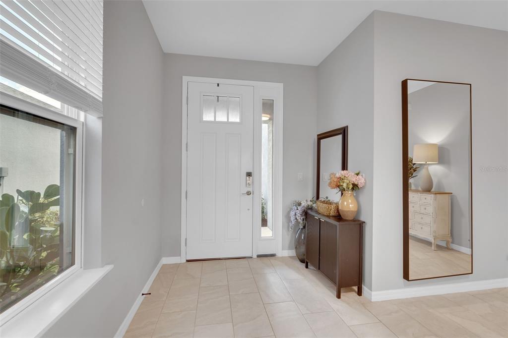 An entryway features a white front door, tile flooring, a console table, and a floor mirror — 5659 EQUATOR COURT, NOKOMIS, FL