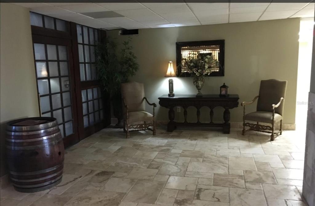 A lobby with stone tile flooring, two armchairs, a console table, and a wooden barrel — 3501 S ATLANTIC AVENUE UNIT 5030, DAYTONA BEACH, FL