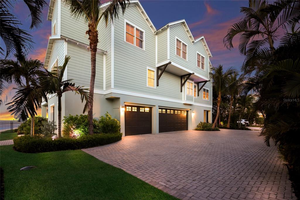 A multi-story house with light green siding, two garage doors, and a brick driveway — 526 56TH STREET, HOLMES BEACH, FL