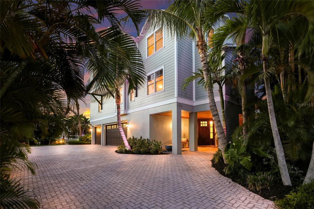 A three-story house with light siding and a paved driveway surrounded by palm trees — 526 56TH STREET, HOLMES BEACH, FL
