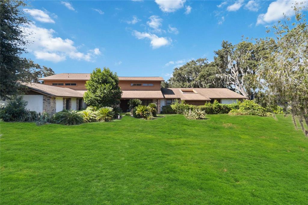 A two-story house with a brown shingled roof sits behind a large, grassy lawn — 4226 DOWNEAST LANE, WINDERMERE, FL