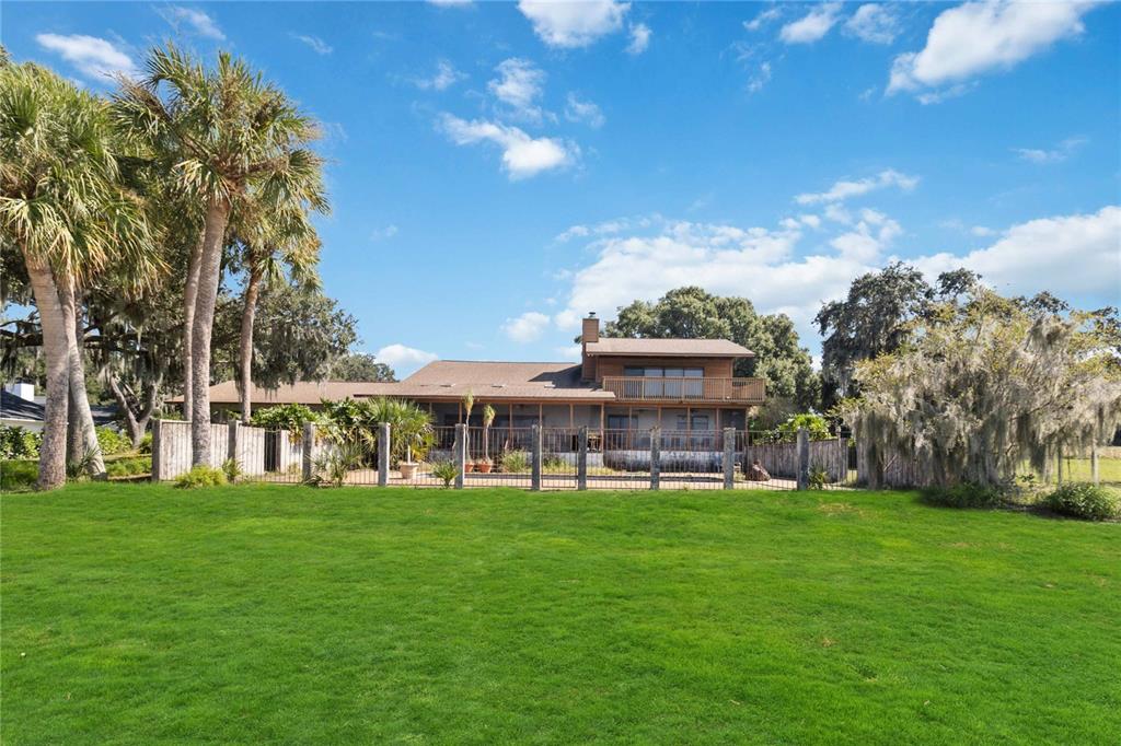 A two-story wooden house with a fenced backyard and palm trees under a blue sky — 4226 DOWNEAST LANE, WINDERMERE, FL
