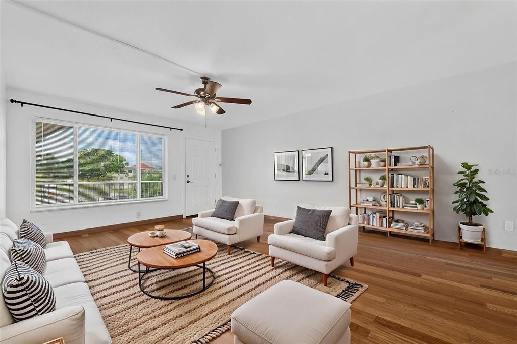 A living room features white furniture, a wooden bookshelf, a ceiling fan, and hardwood floors — 2433 BRAZILIA DRIVE UNIT 49, CLEARWATER, FL