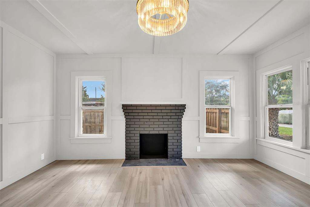 A living room features white paneled walls, light wood flooring, and a dark brick fireplace — 5355 2ND AVENUE S, ST PETERSBURG, FL