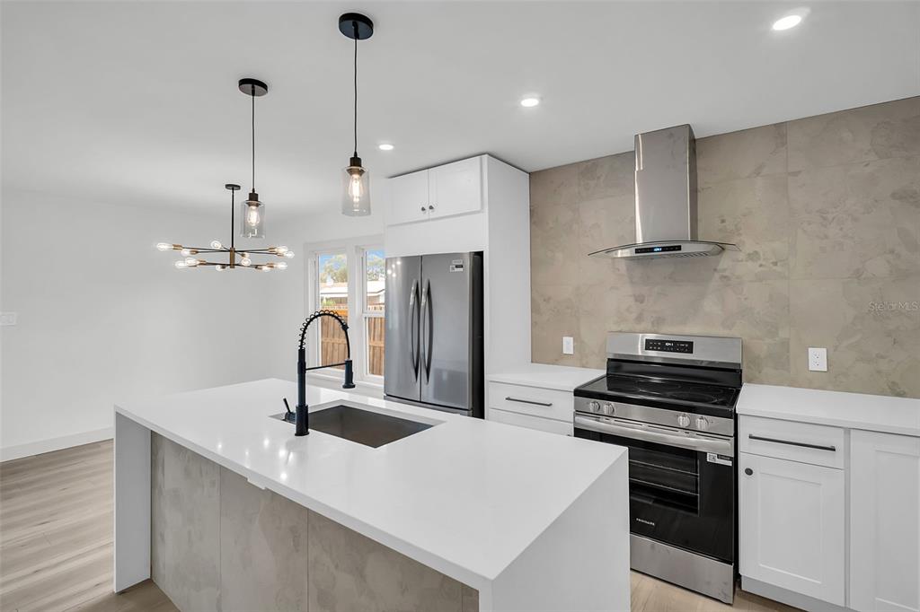 A modern kitchen features a white quartz island, stainless steel appliances, and a tiled backsplash — 5355 2ND AVENUE S, ST PETERSBURG, FL