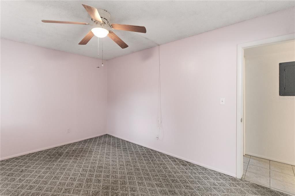 An empty bedroom features pale pink walls, patterned gray carpeting, and a ceiling fan — 521 MIDWAY DRIVE UNIT B, OCALA, FL