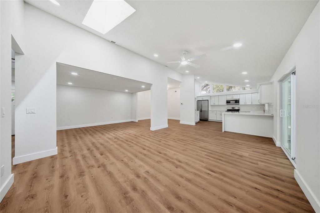 A virtually staged open-concept living and dining area with vaulted ceilings and wood-look flooring — 2104 DOEFIELD COURT, VALRICO, FL