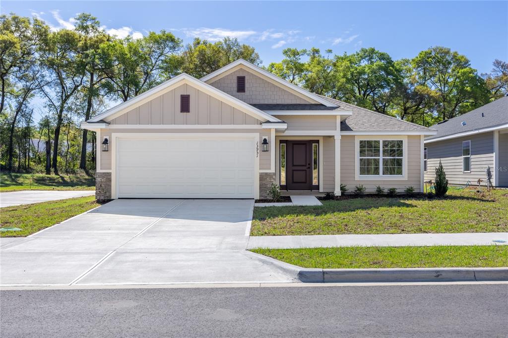 A single-story suburban house with a two-car garage, tan siding, and a dark front door — 17788 NW 168TH ROAD, ALACHUA, FL