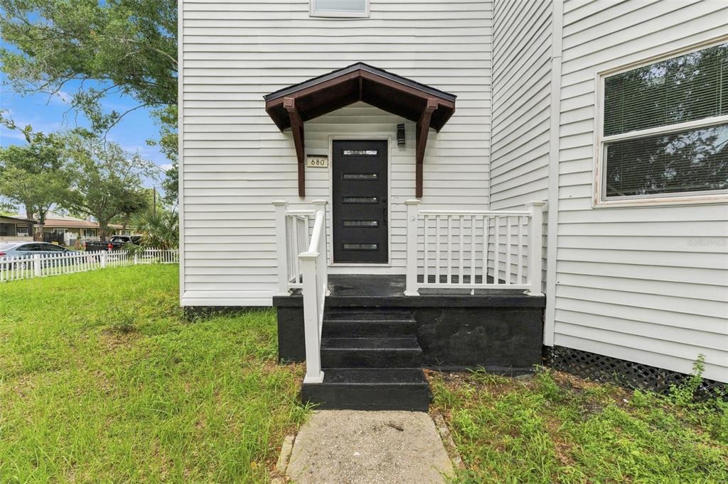 A room with light wood flooring, a staircase, an arcade cabinet, and a cowhide rug — 680 25TH AVENUE S, ST PETERSBURG, FL