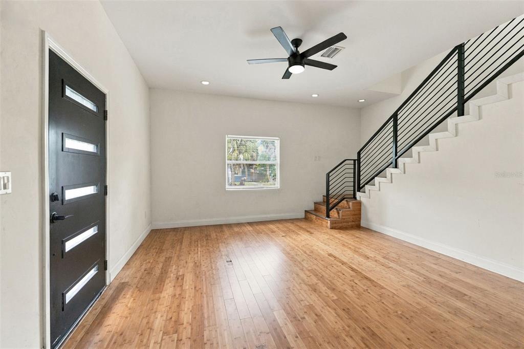 A modern kitchen features black cabinets, a white quartz island with green stools, and wood flooring — 680 25TH AVENUE S, ST PETERSBURG, FL