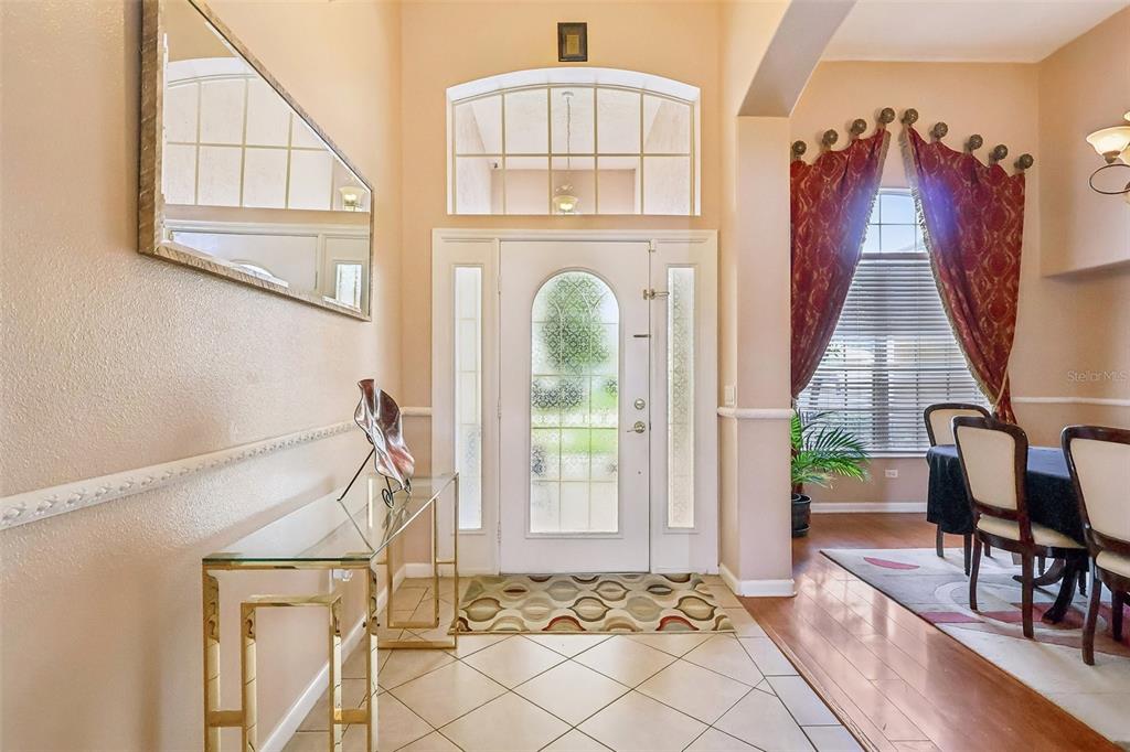 An entryway with tile flooring, a glass console table, and a white front door — 84 BRAELOCK DRIVE, OCOEE, FL