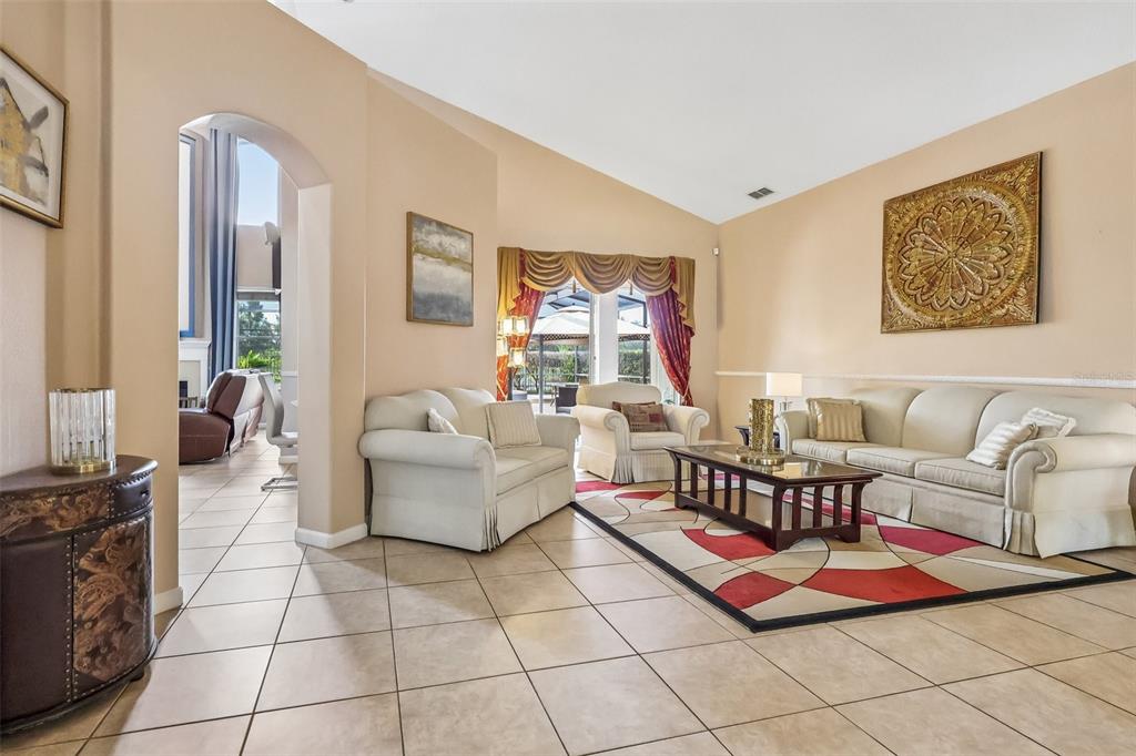 A living room features beige tile floors, a vaulted ceiling, and a patterned area rug — 84 BRAELOCK DRIVE, OCOEE, FL