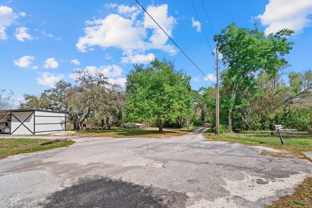 An outdoor view of a paved road leading toward a white barn and trees — INDALE DRIVE, NEW PORT RICHEY, FL
