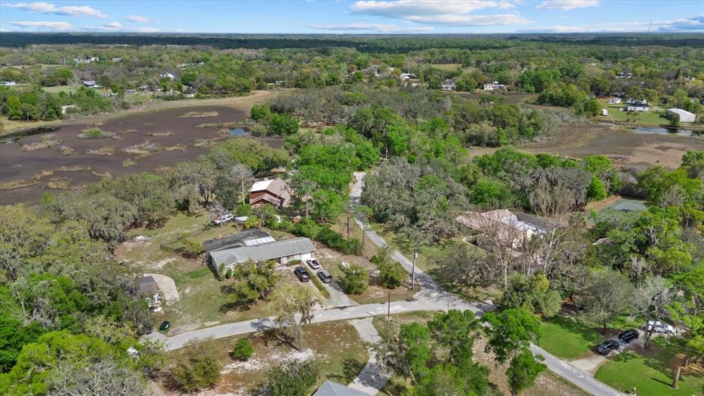 An aerial view shows a residential property with a house, driveway, and surrounding wooded landscape — INDALE DRIVE, NEW PORT RICHEY, FL