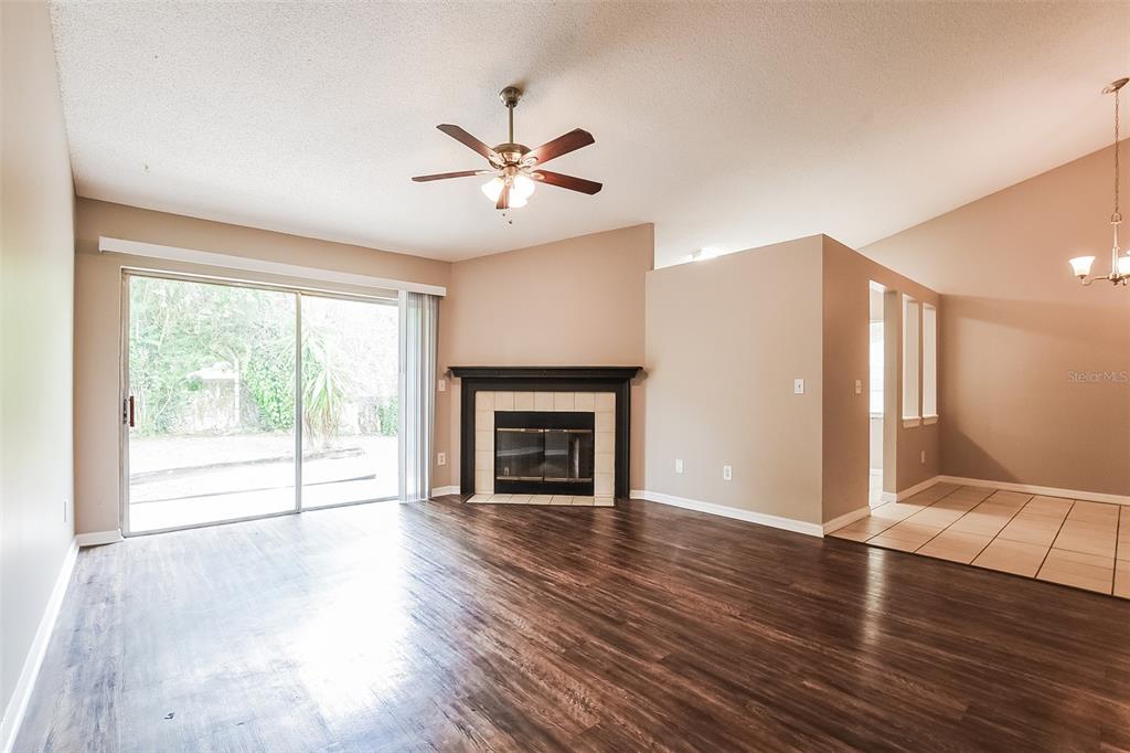 A living room with dark wood flooring, a fireplace, and a sliding glass door — 337 MANTIS LOOP, APOPKA, FL