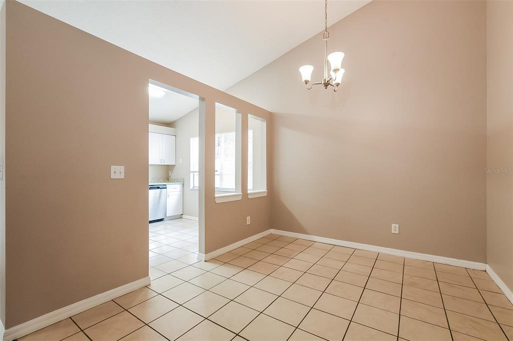 A dining area with beige walls, tile flooring, a vaulted ceiling, and a chandelier — 337 MANTIS LOOP, APOPKA, FL