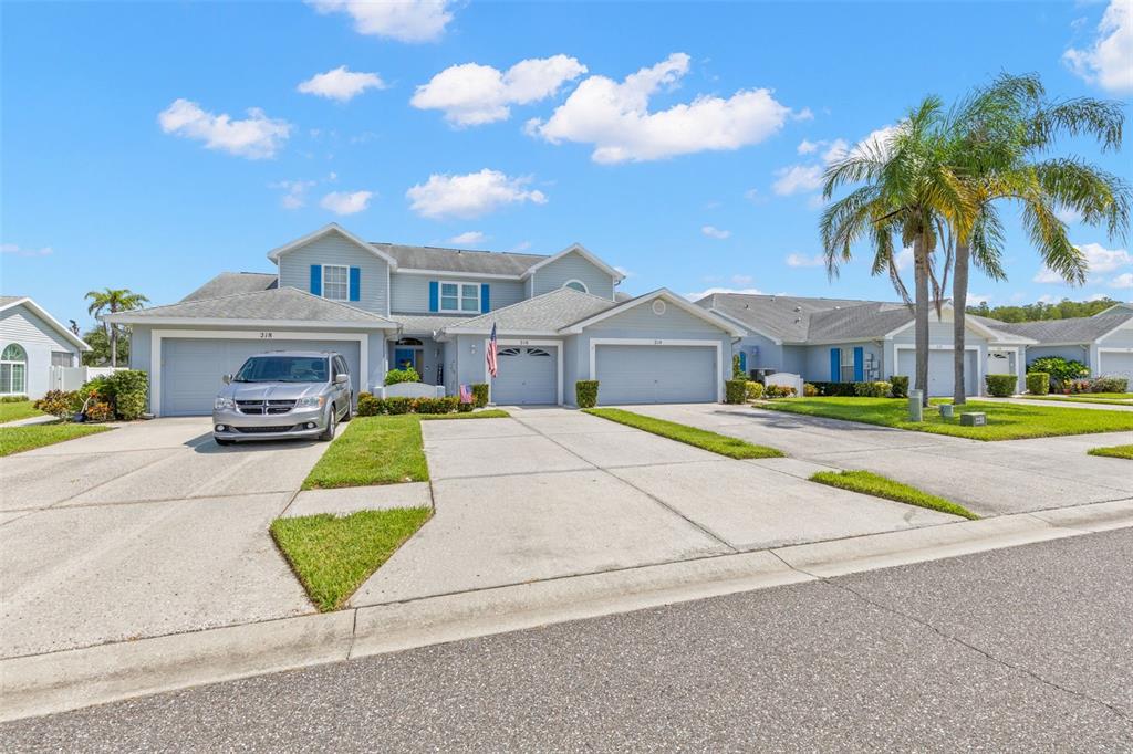 A light blue two-story house with a three-car garage and a paved driveway — 216 HEMINGWAY DRIVE, OLDSMAR, FL