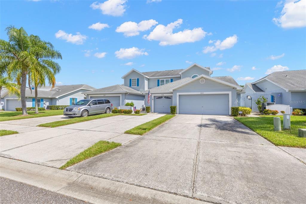 A two-story light blue house with a three-car garage and a concrete driveway — 216 HEMINGWAY DRIVE, OLDSMAR, FL