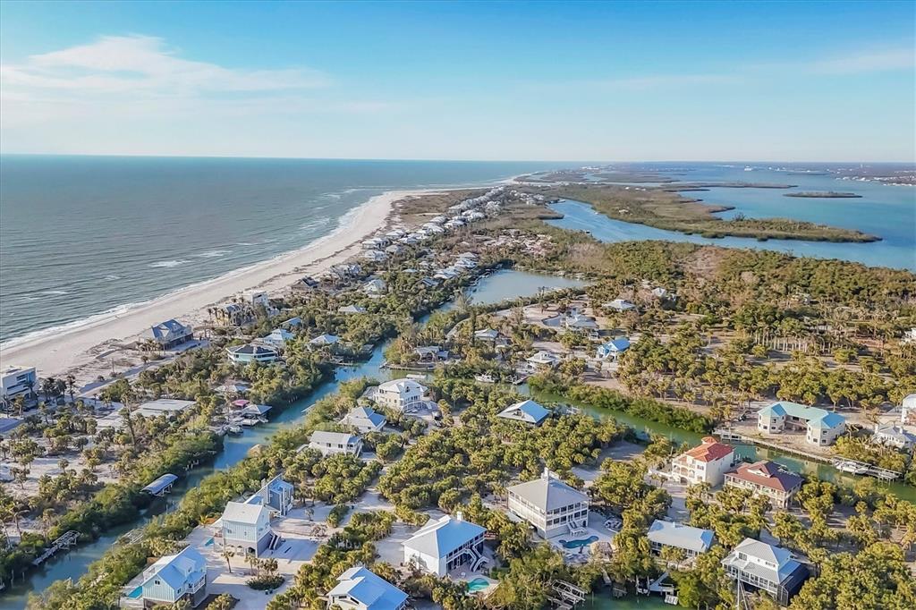 An aerial view shows coastal homes nestled among trees along a beach and winding canals — 51 PALM DRIVE, PLACIDA, FL