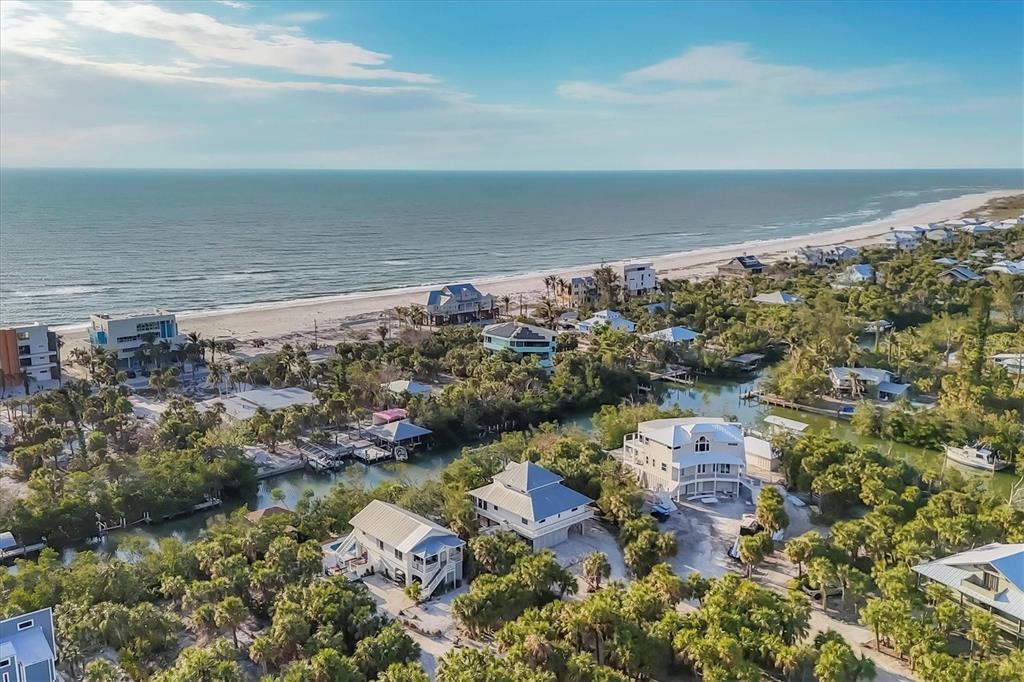 An aerial view shows coastal houses nestled among trees near a sandy beach and ocean — 51 PALM DRIVE, PLACIDA, FL