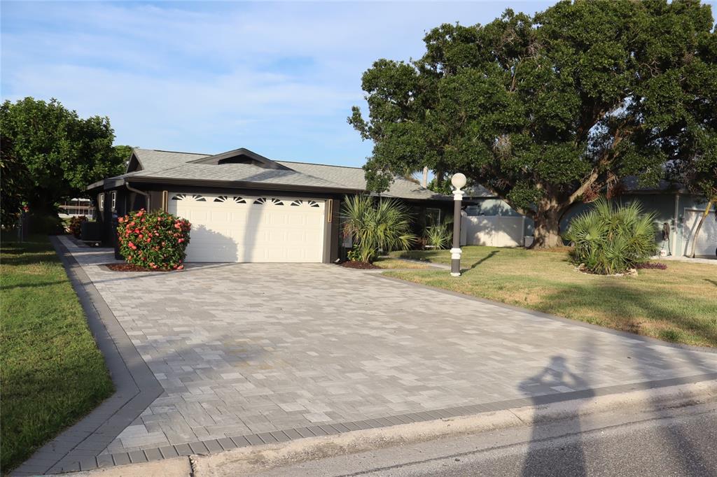 A single-story house features a paved driveway, a two-car garage, and mature trees — 1019 SPINDLE PALM WAY, APOLLO BEACH, FL