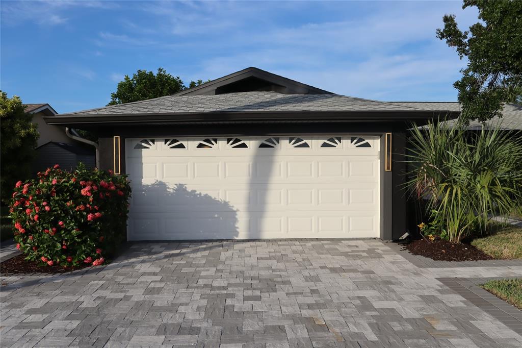 A white two-car garage door with decorative windows sits beneath a dark-trimmed roof — 1019 SPINDLE PALM WAY, APOLLO BEACH, FL