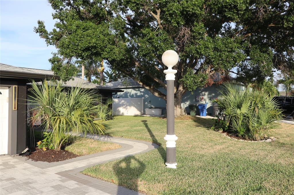 A paved walkway leads through a grassy yard toward a house with a globe lamp — 1019 SPINDLE PALM WAY, APOLLO BEACH, FL