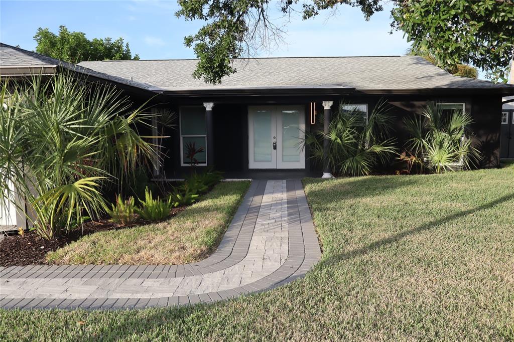 A dark-painted house features a paved walkway leading to a double-door entrance with columns — 1019 SPINDLE PALM WAY, APOLLO BEACH, FL