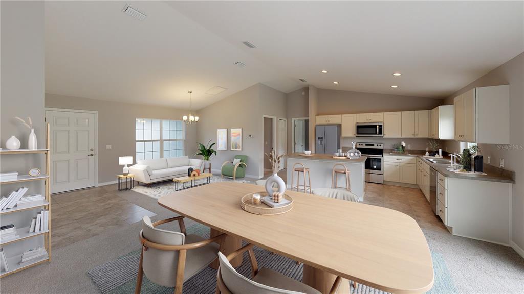 An open-concept living and dining area features light-colored cabinetry, tile flooring, and vaulted ceilings — 1699 NE 161ST STREET, CITRA, FL
