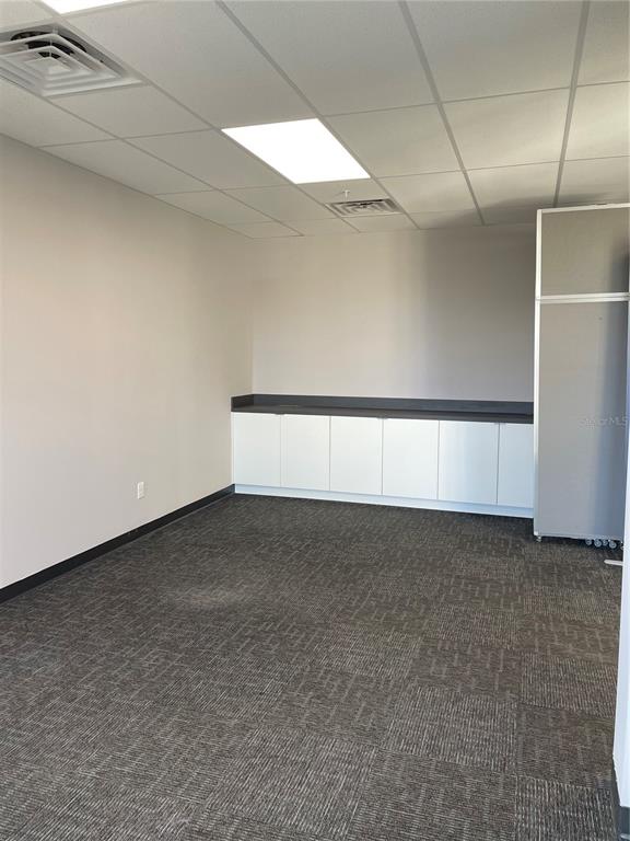 An office room features gray carpet, white cabinets with a dark countertop, and ceiling lights — 13550 VILLAGE PARK DRIVE UNIT 345, ORLANDO, FL