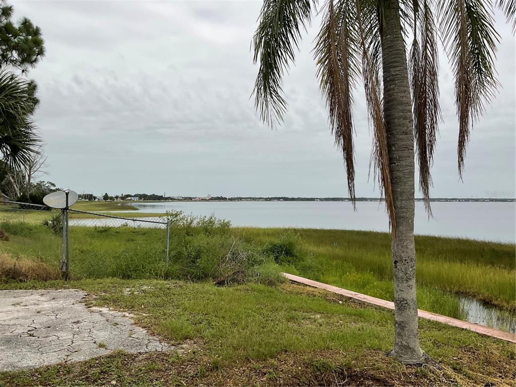 A view of a lake from a grassy yard with a palm tree and fence — 1025 LAKEVIEW DRIVE, SEBRING, FL