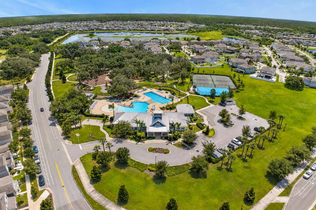 An aerial view shows a community clubhouse with a swimming pool, tennis courts, and parking — 12826 WILDFLOWER MEADOW DRIVE, RIVERVIEW, FL