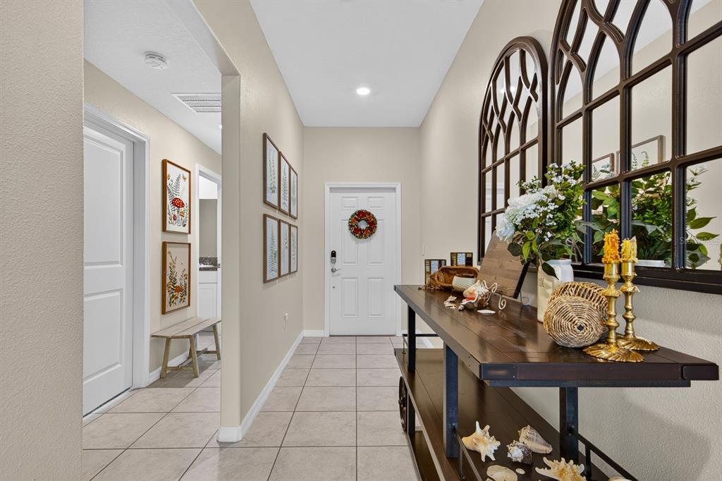 A tiled entryway features a console table, arched wall mirrors, and a white front door — 12826 WILDFLOWER MEADOW DRIVE, RIVERVIEW, FL