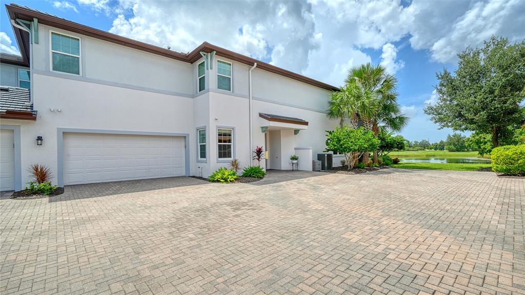 A two-story house with a paved driveway, a two-car garage, and a nearby pond — 7552 DIVOT LOOP, BRADENTON, FL