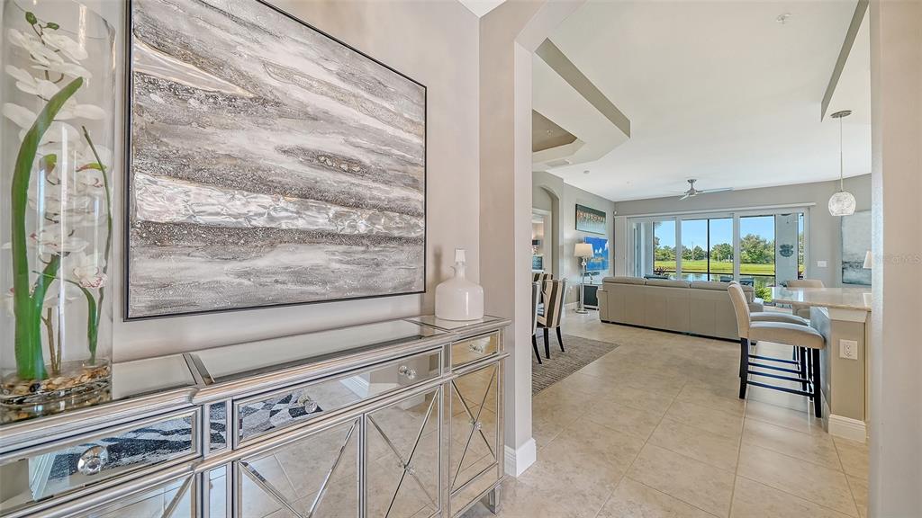 A mirrored console table sits in a foyer leading to an open-concept living area — 7552 DIVOT LOOP, BRADENTON, FL